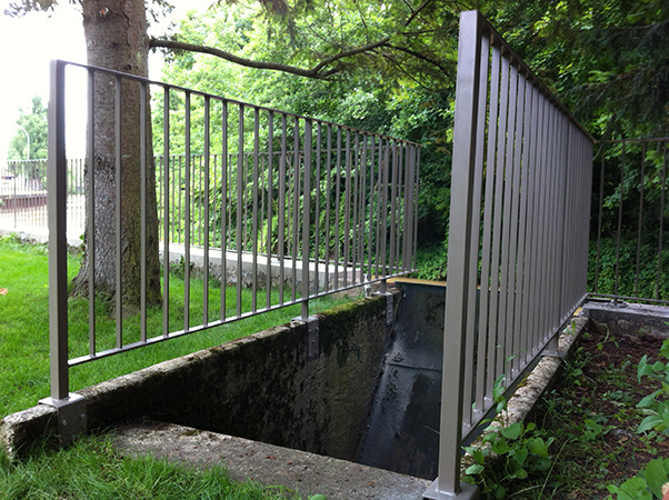 Garde corps clôture le long d'un canal. Clôture chevillée sur mur béton avec barreaudage en plat pour le passage des crues du canal