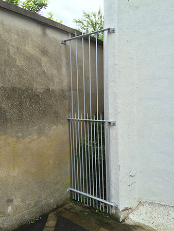 Petite grille de défense dans une ruelle, entre un mur et un bâtiment